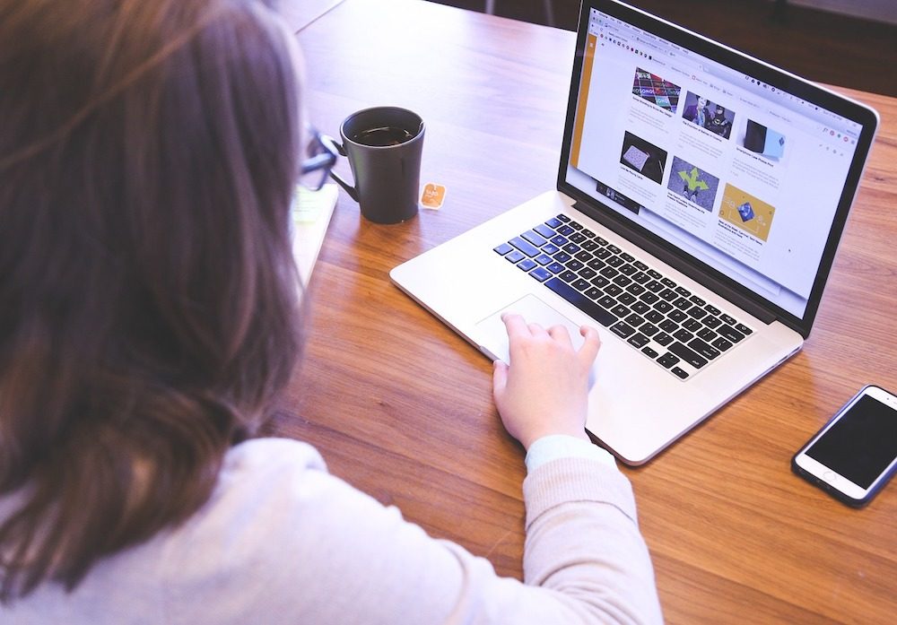 Eine Frau mit einer Tasse Tee an Ihrem Schreibtisch von Ihrem Laptop