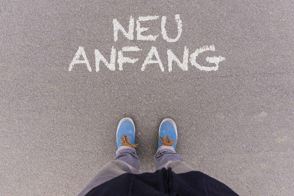 Ein Mensch steht vor dem Wort "neu Anfang" auf dem Boden